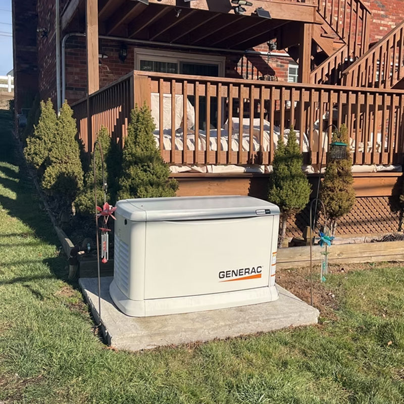 Generac standby generator on a poured pad beside a deck